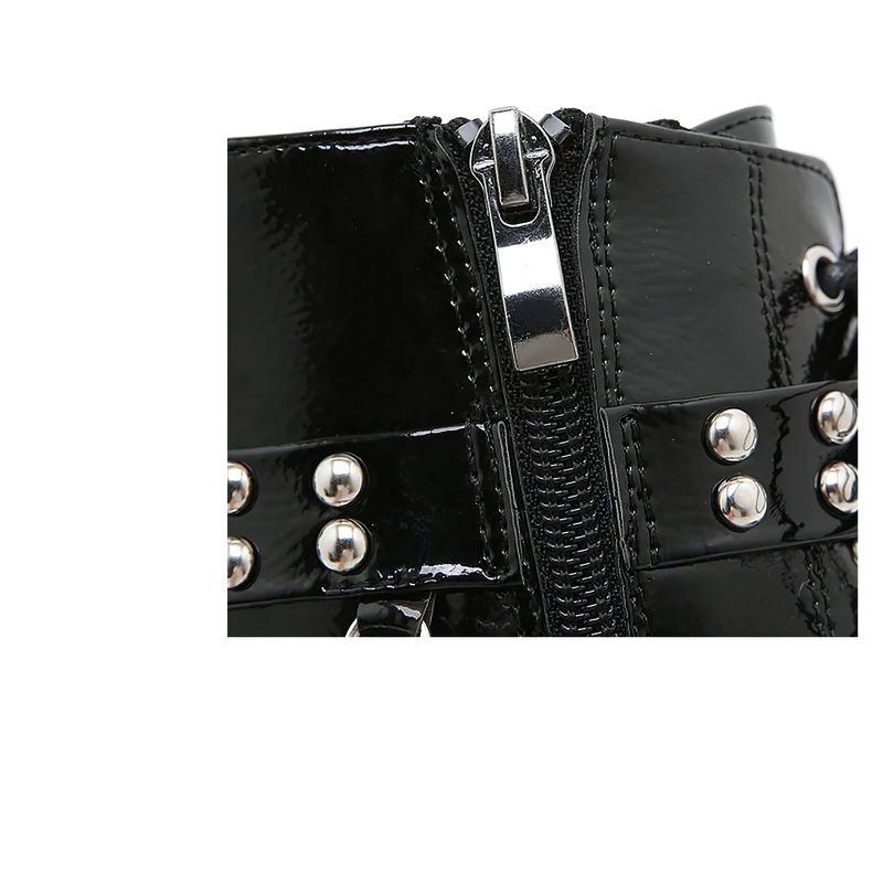 Close-up of stylish women's motorcycle ankle boots with shiny patent leather and metal stud detailing.