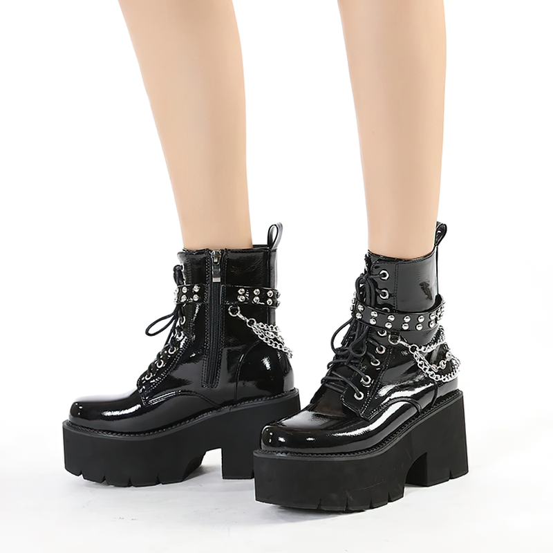 Women's black patent leather motorcycle ankle boots with metal chain accents and chunky platform.