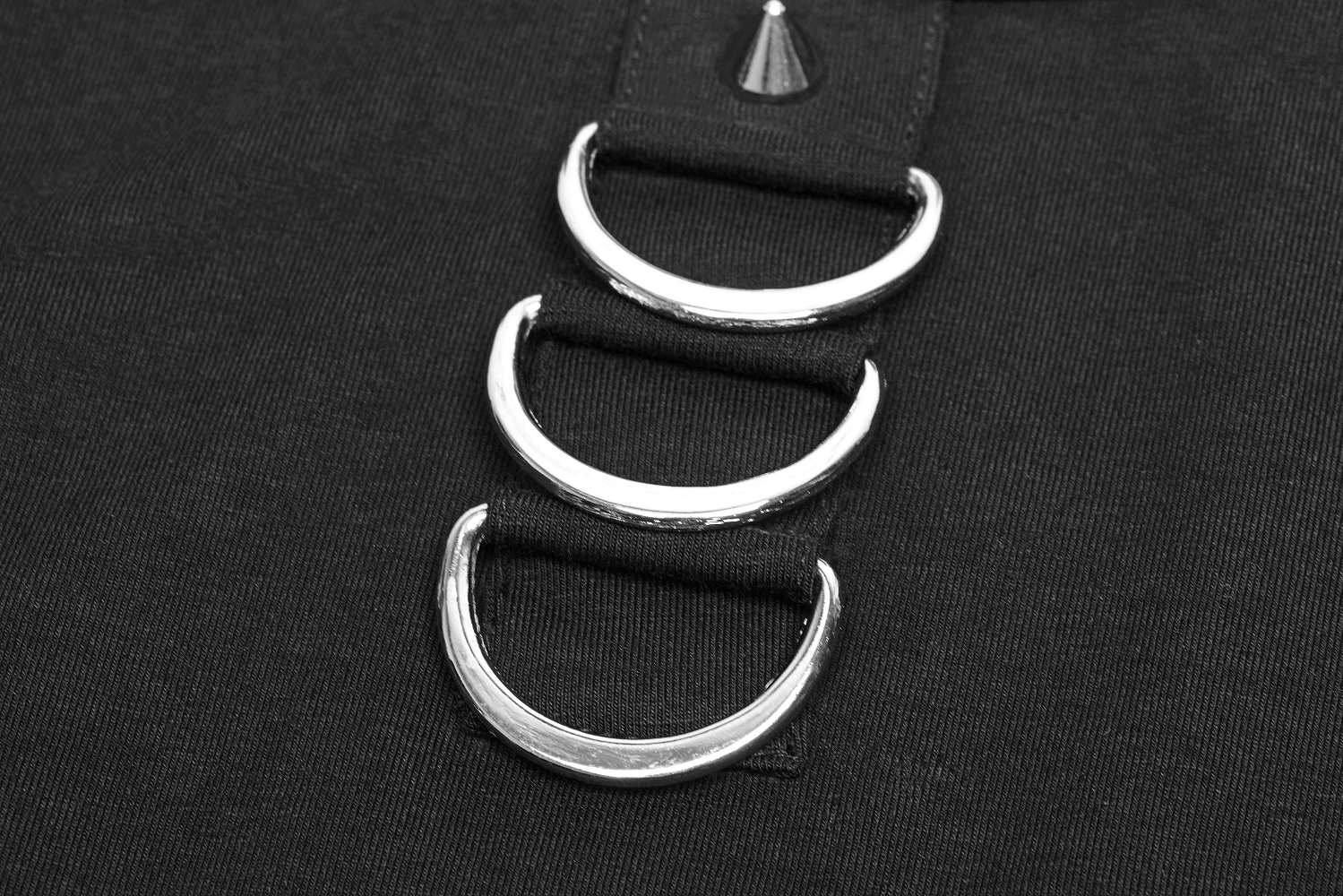 Close-up of black sweatshirt featuring silver rings and punk-inspired detailing.