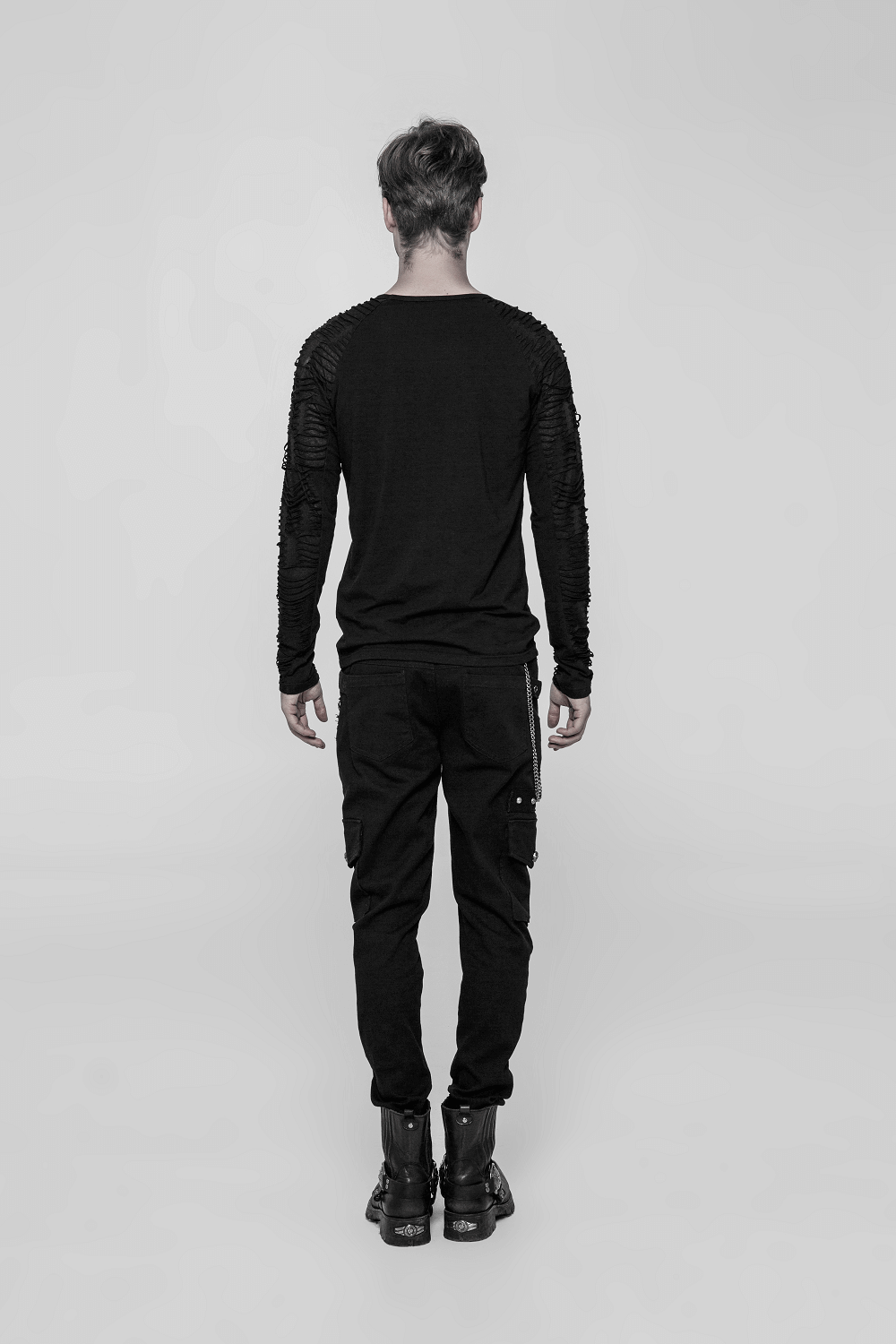 Back view of a man wearing a black sweatshirt with ripped knit sleeves and cargo pants.