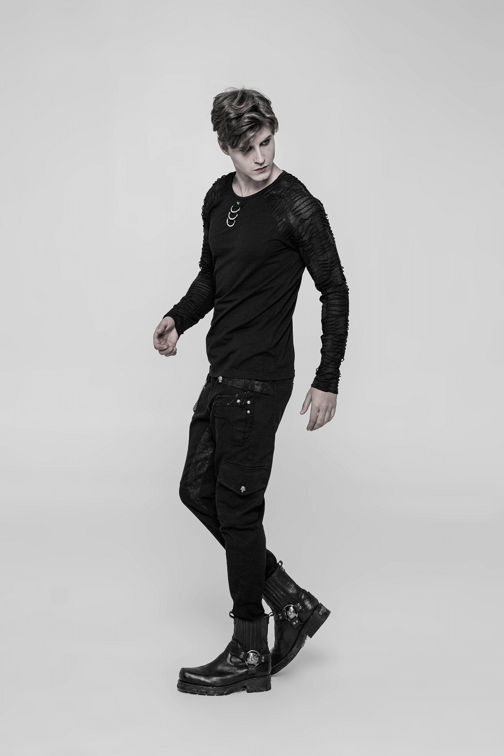 Stylish man in a black sweatshirt with ripped sleeves and punk style pants, showcasing edgy urban fashion.