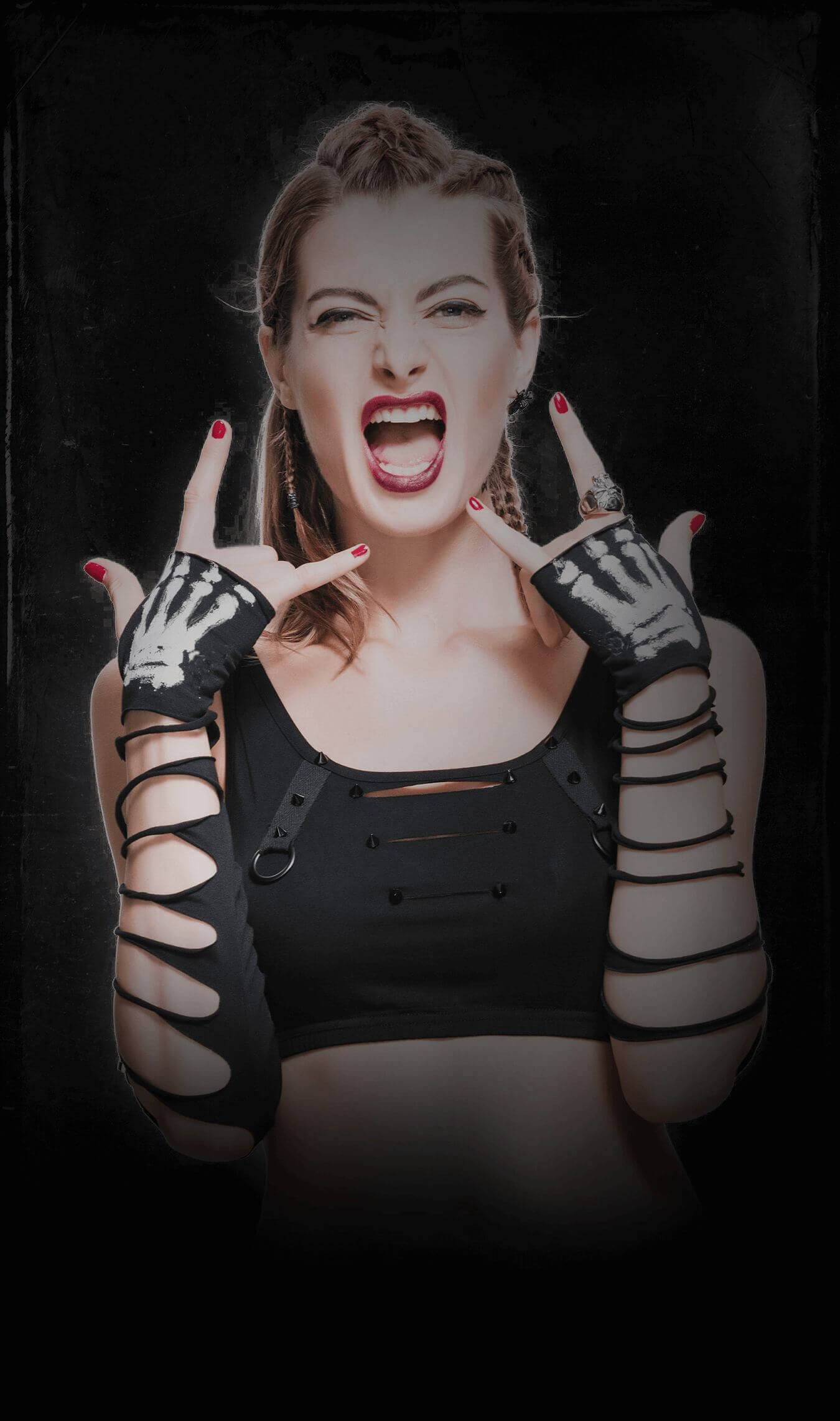 Rock-inspired collection: woman in black cut-out top and fingerless gloves making rock n' roll hand sign with a bold, rebellious expression.