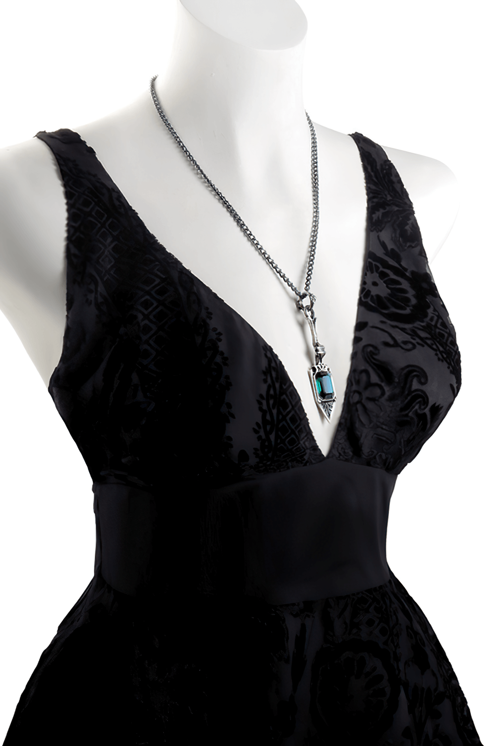 Elegant absinthe spoon pendant with emerald green crystal on a black dress, showcasing timeless style.