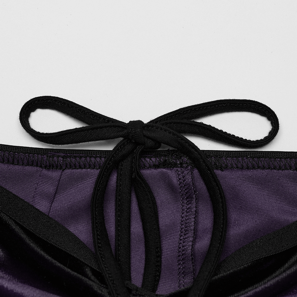 Close-up of a black tie detail on deep purple fabric showcasing vintage-inspired style.