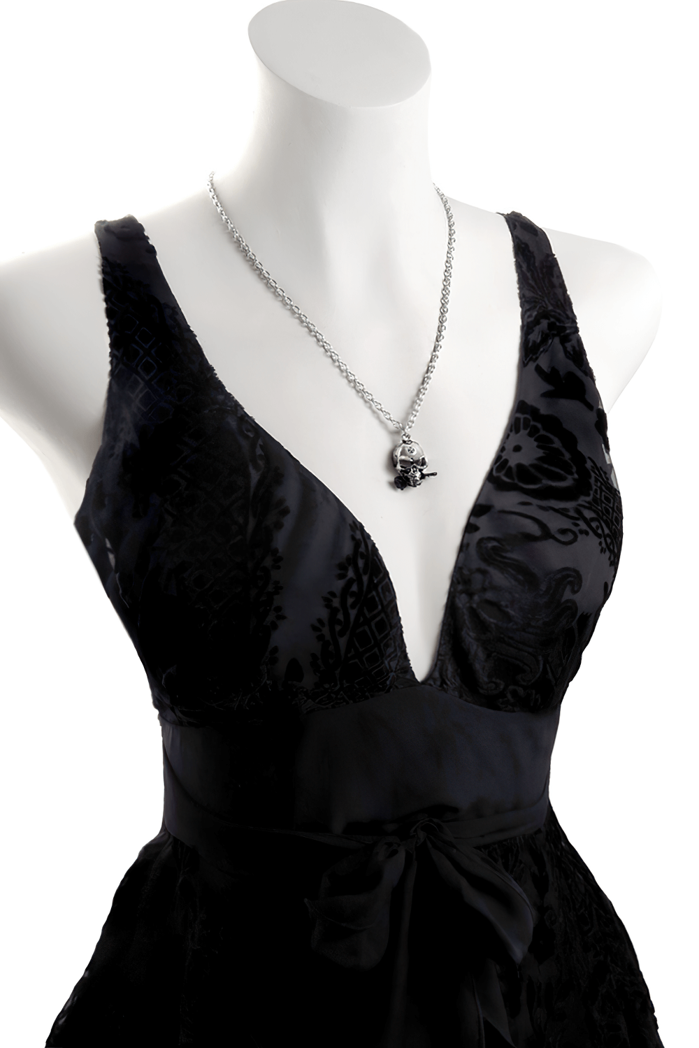 Alchemist skull pendant with black rose accent displayed on a stylish black dress, showcasing gothic jewelry elegance.