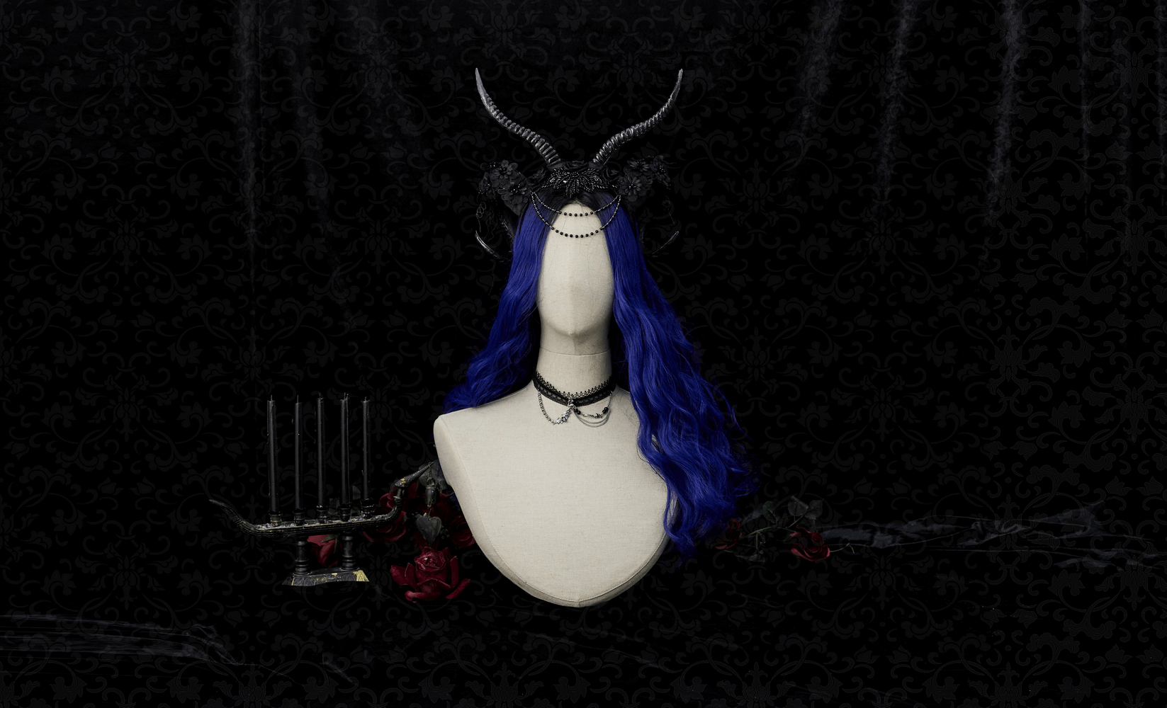 Gothic horned headpiece with lace detail and blue hair on mannequin, surrounded by roses.
