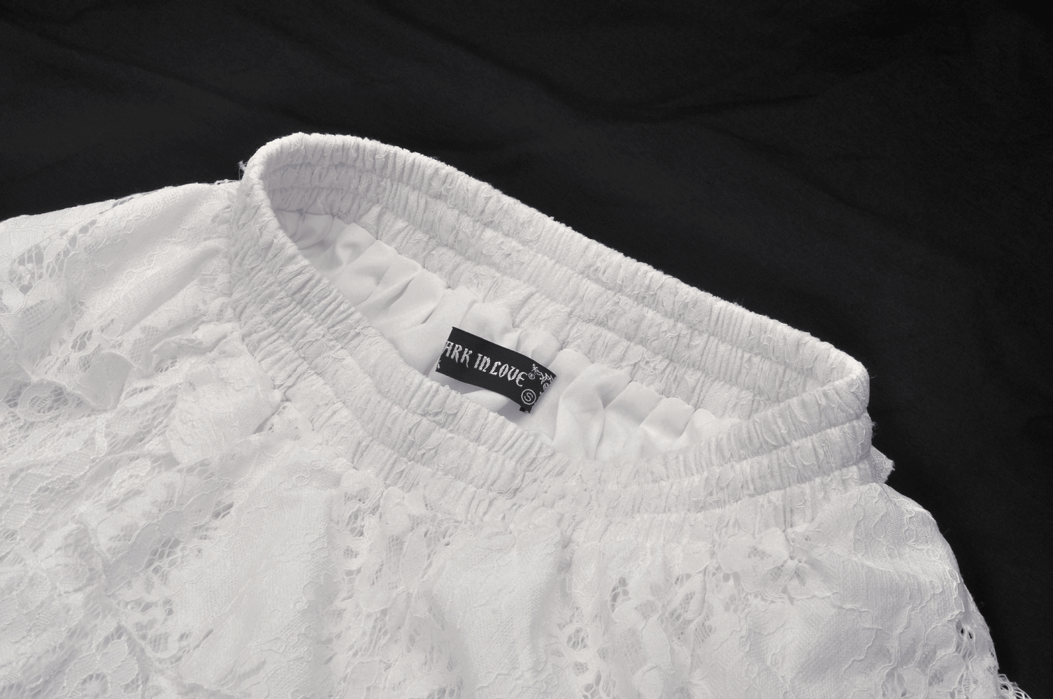 Close-up of the waistband of an ethereal white lace mini skirt, featuring a stretchy elastic band for comfort.