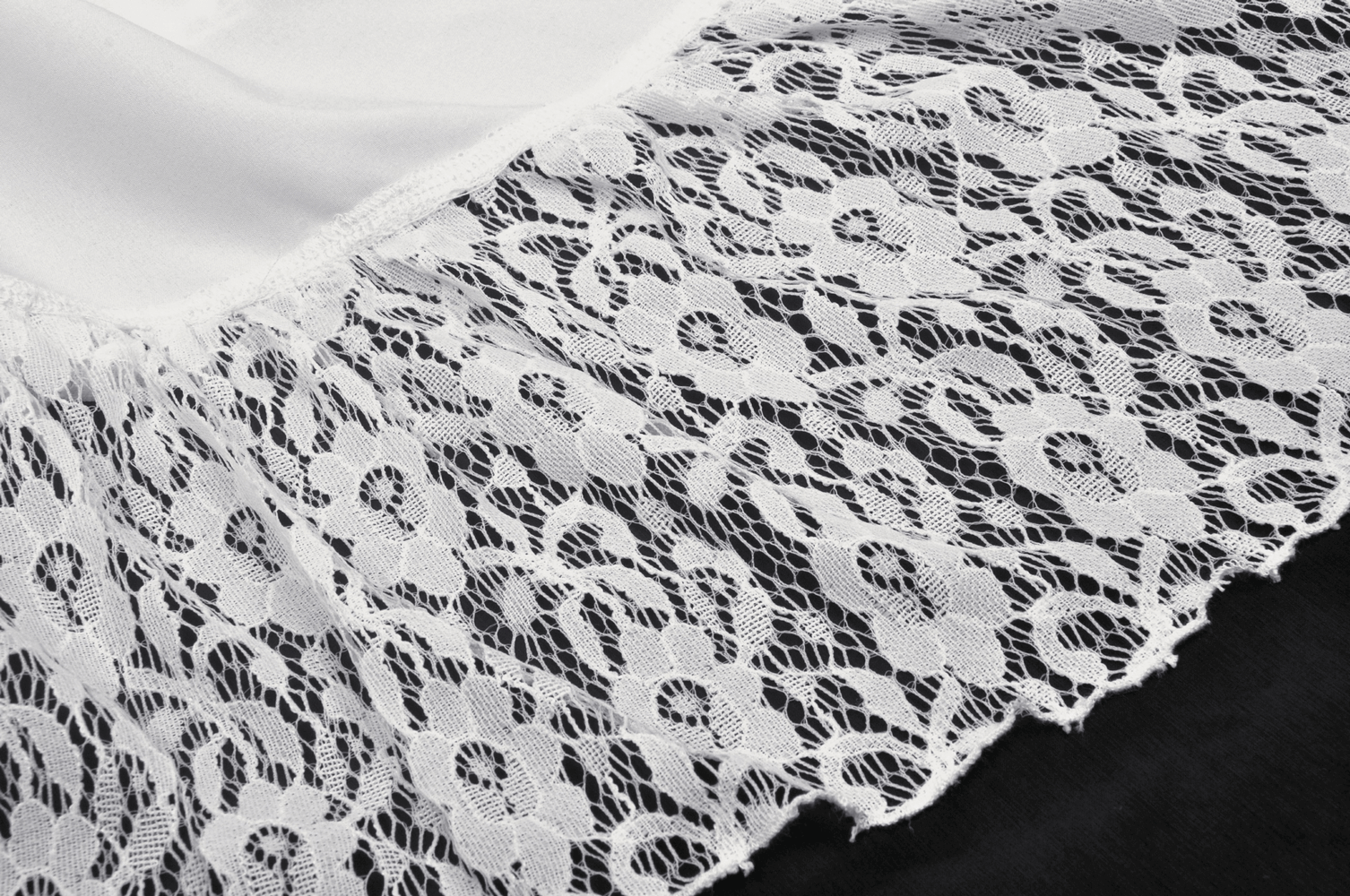 Close-up of delicate white lace trim showcasing intricate floral patterns for a gothic-inspired mini skirt.