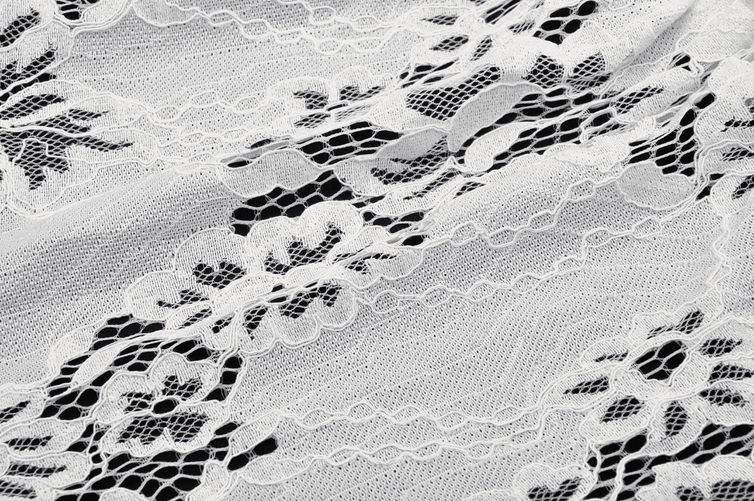 Textured white lace fabric showcasing delicate floral patterns and intricate details, ideal for fashion and elegant designs.