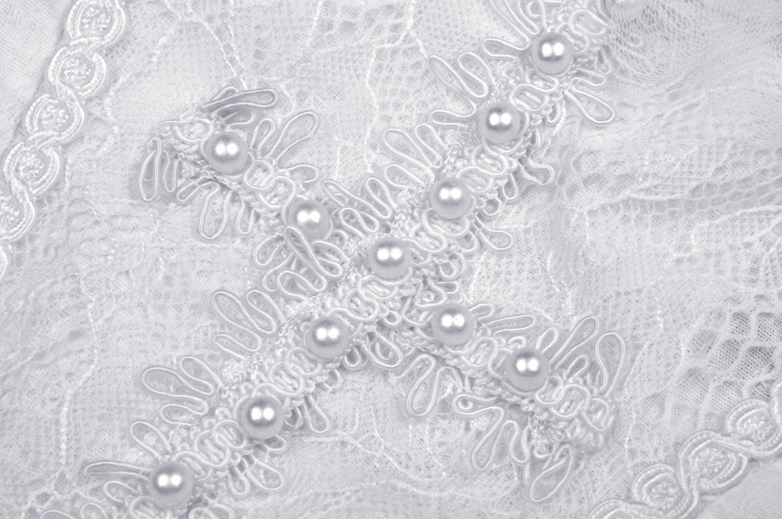 White lace detail with pearl beading on the cross-chest design of a Gothic Lolita mini dress.