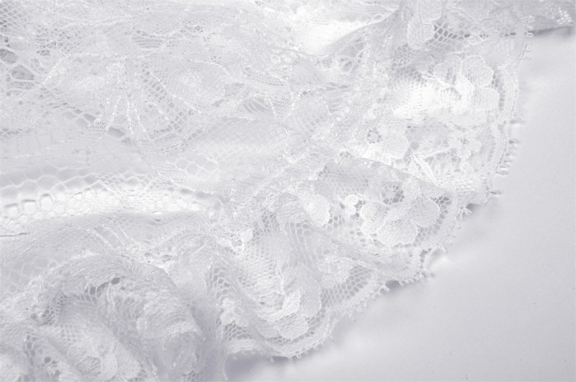 Close-up of delicate white lace fabric with floral patterns, perfect for gothic Lolita dresses.
