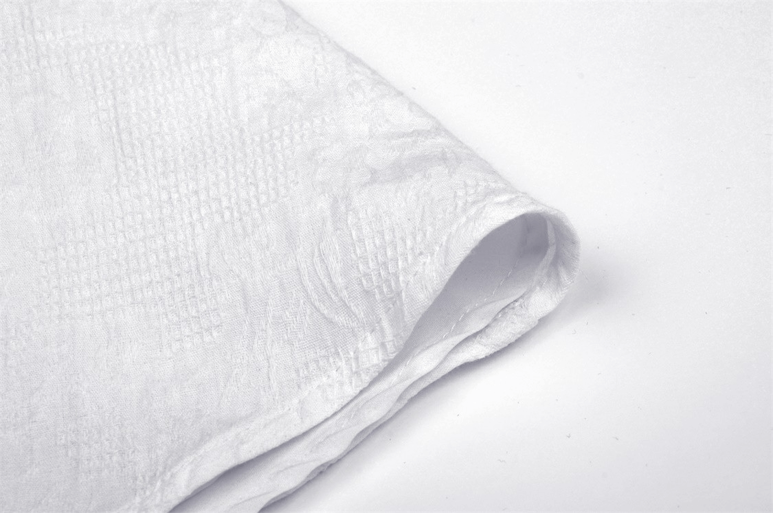 Soft white fabric close-up, showcasing a textured pattern perfect for crafting elegant garments.