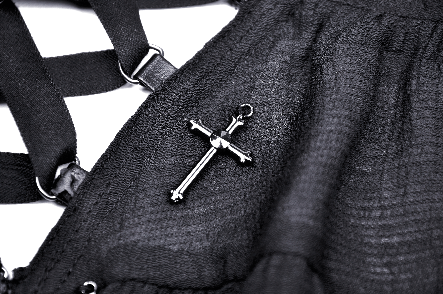 Black cross pendant on gothic outfit fabric, perfect for punk and alternative fashion styles.