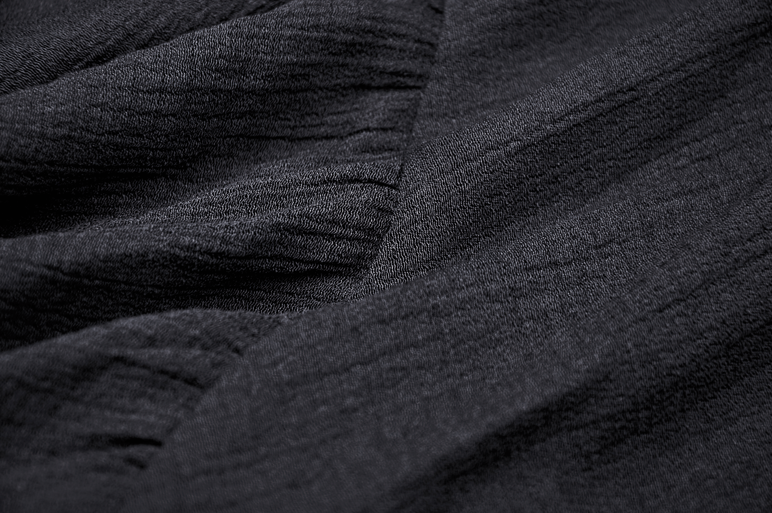 Close-up of lightweight black fabric showcasing textured layers for a punk or witchy skirt design.