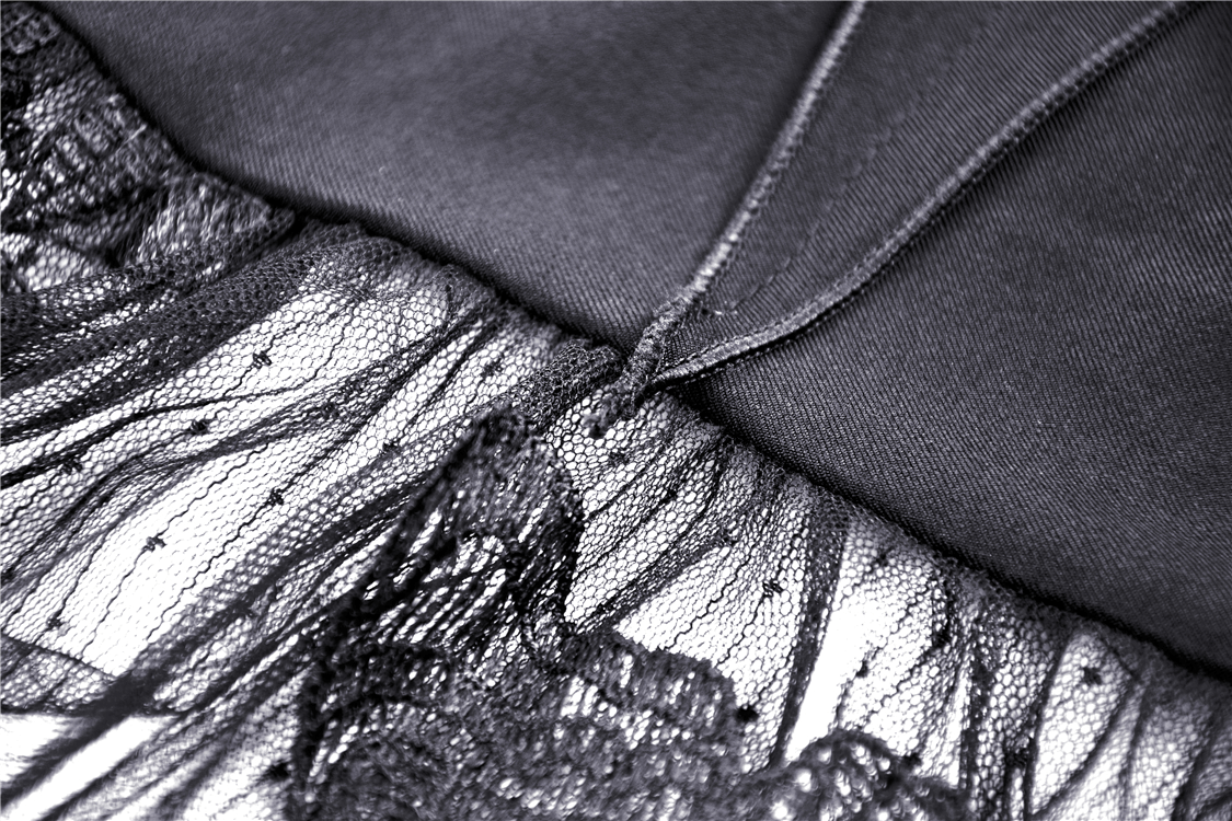 Close-up of asymmetrical dress detailing with butterfly straps and floral embroidery in black fabric.