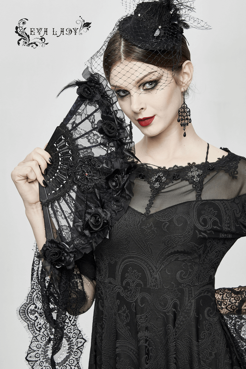 Elegant model in black lace dress, holding a decorative fan, showcasing gothic fashion with intricate details.