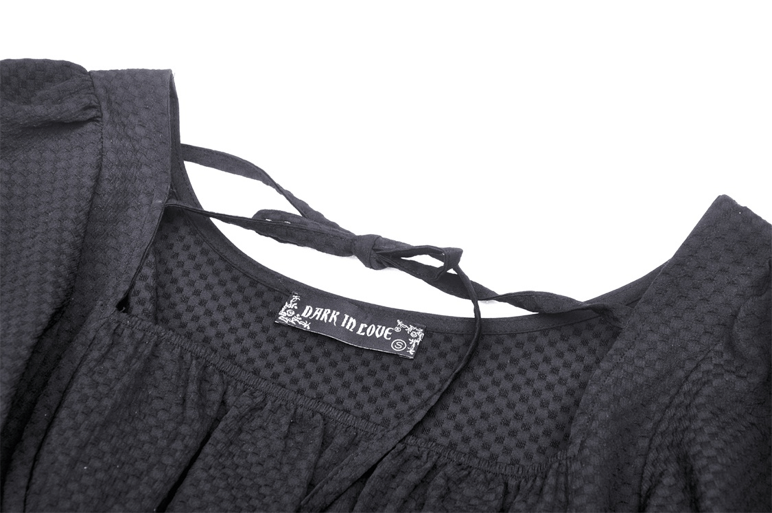 Close-up of the black dress neckline with 'Dark in Love' label, showcasing unique textured fabric and elegant tie detail.