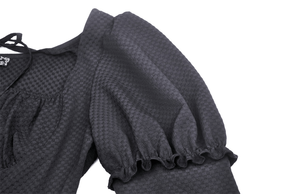 Close-up of the dramatic puffed sleeve and textured fabric of an asymmetrical black lace dress.