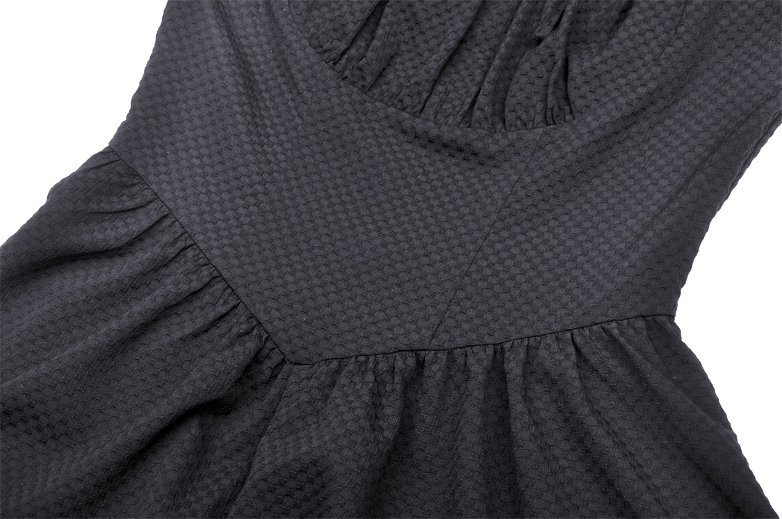 Close-up of the textured black fabric of an asymmetrical hem dress with long sleeves and elegant choker neckline.