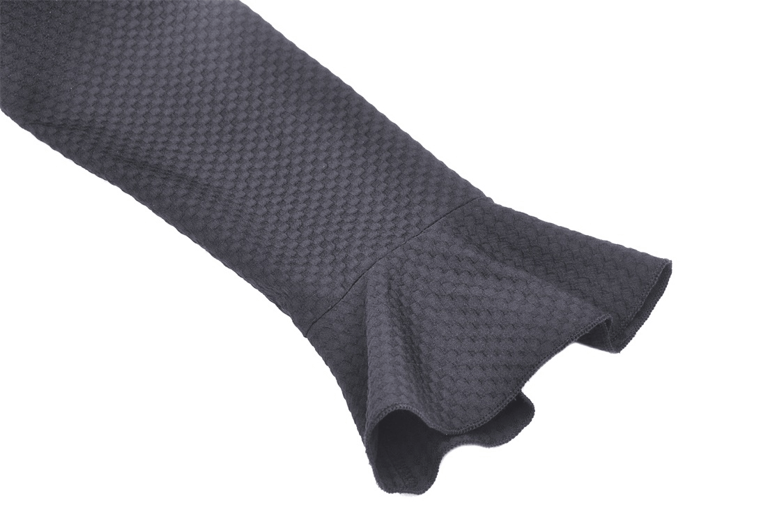Close-up of a black dress sleeve featuring a stylish ruffled hem and textured fabric for a dramatic flair.