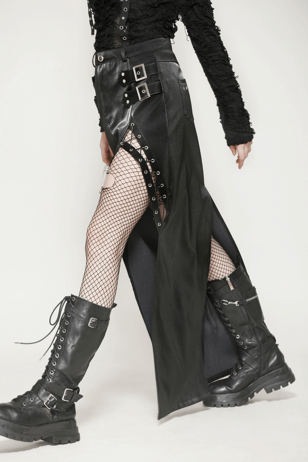 Asymmetrical high-waisted PU leather skirt with buckles, lace-up details, and daring slit, paired with fishnet stockings and combat boots.