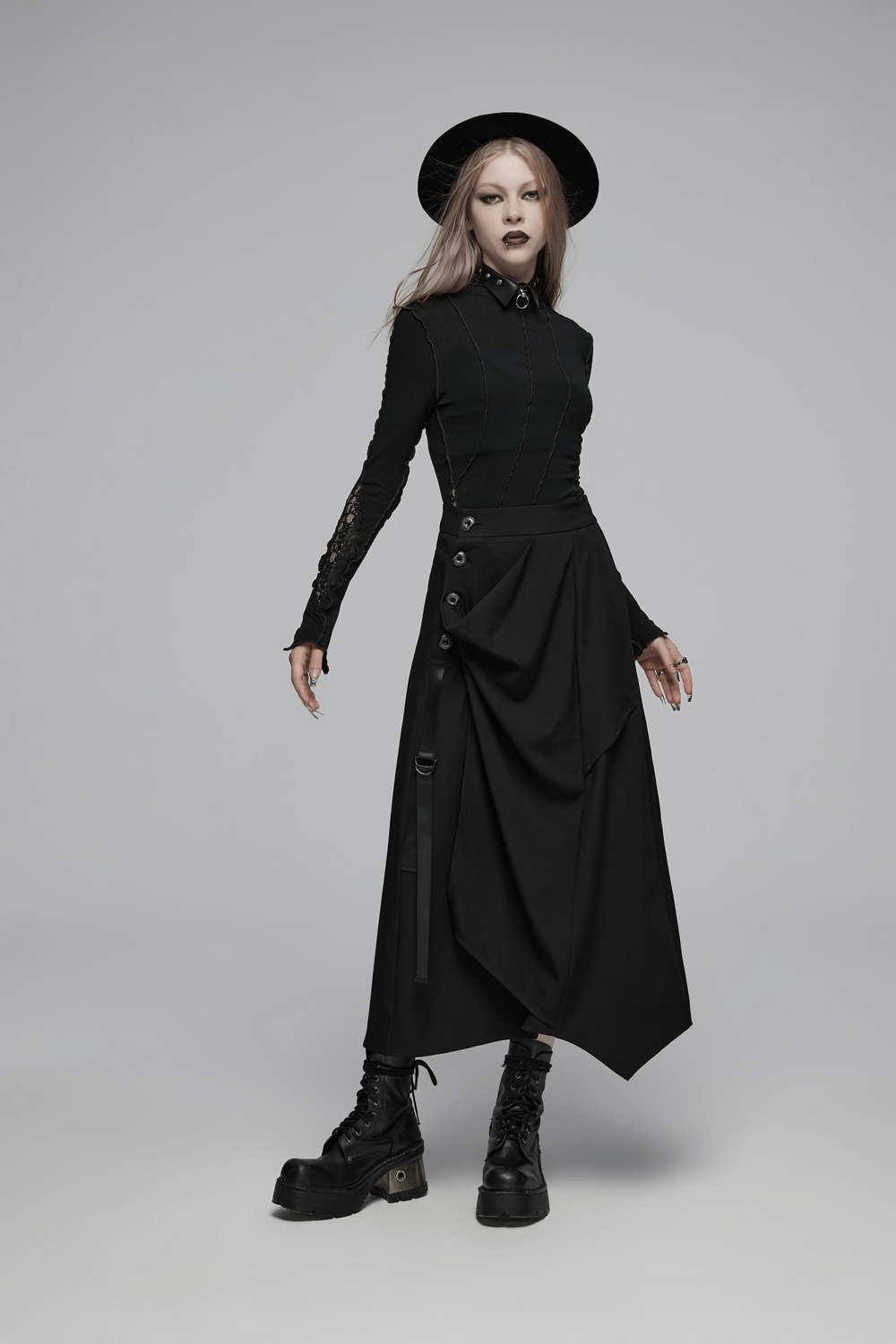 Avant-garde fashion model in asymmetric draped skirt with buckle detail and edgy black outfit.