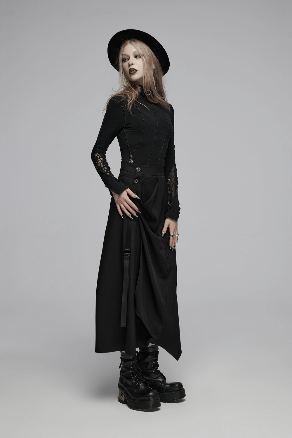 Avant-garde draped skirt with buckle detail, model wearing high-waisted black skirt and edgy style shoes.