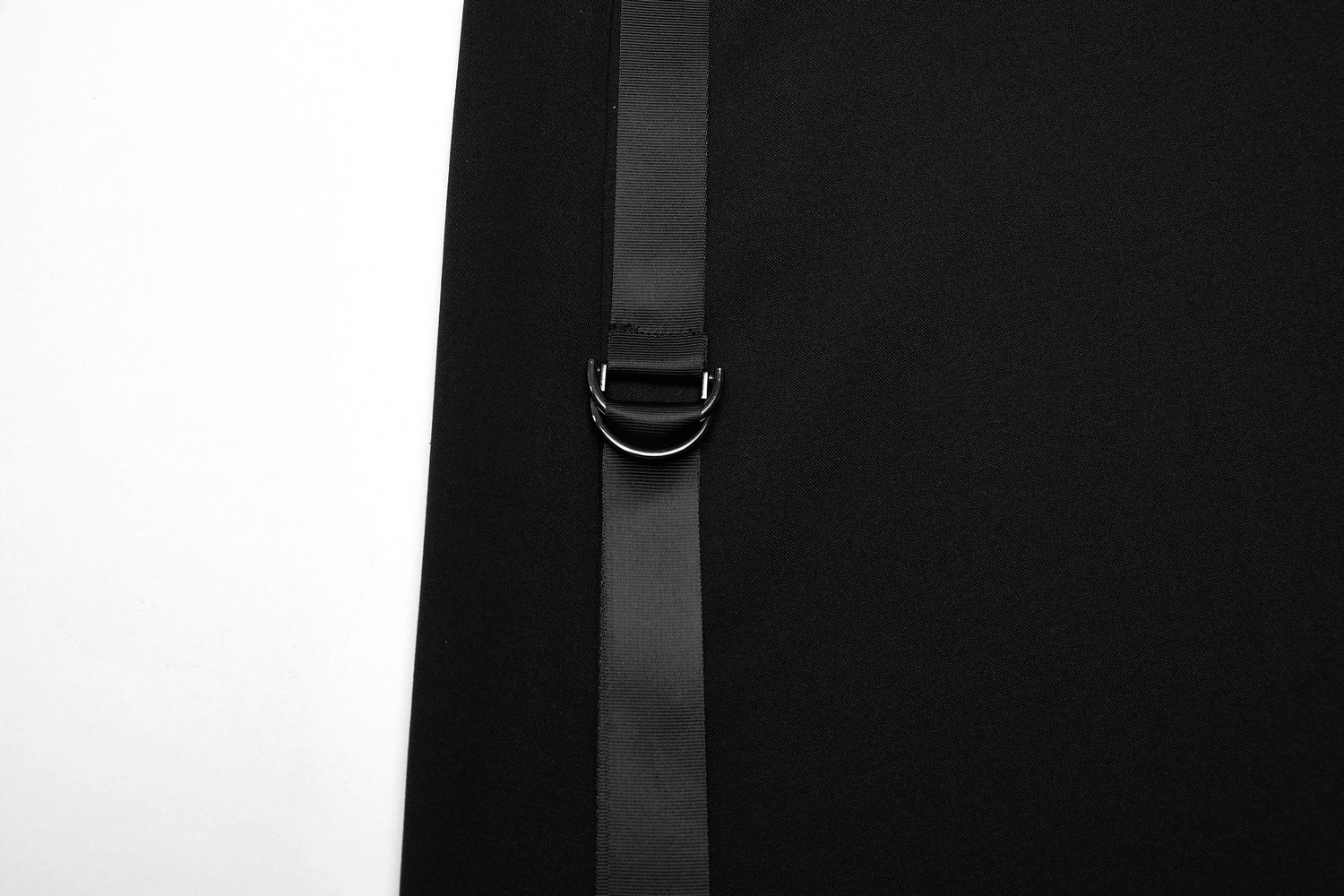 Close-up of buckle detail on avant-garde asymmetric draped skirt in black fabric, showcasing unique design features.