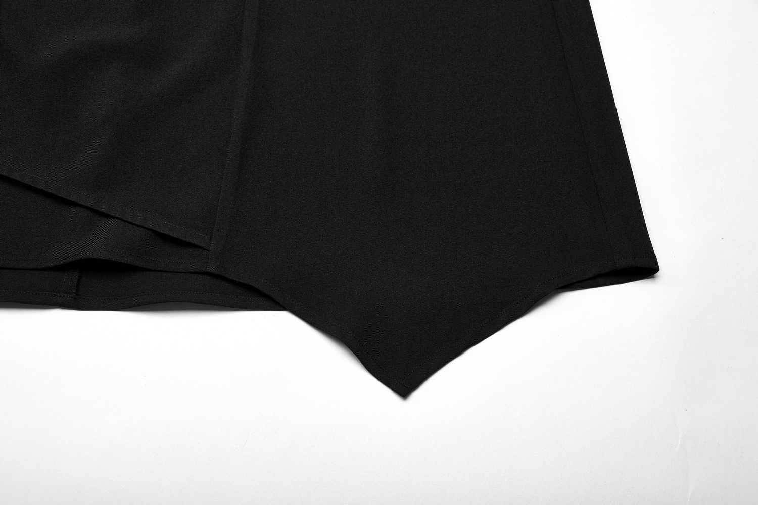 Close-up of avant-garde asymmetric draped skirt hem showcasing the unique cut and sleek black fabric.