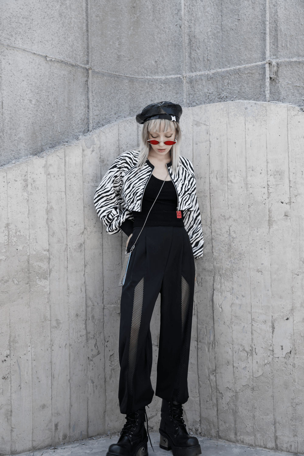 Model showcasing avant-garde black high-waisted wide-leg pants with mesh accents and a stylish zebra jacket.