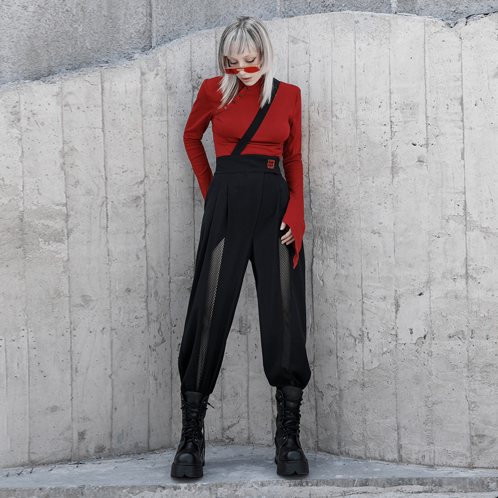 Avant-garde woman in black high-waisted wide-leg pants with mesh accents and red top, showcasing bold fashion style.