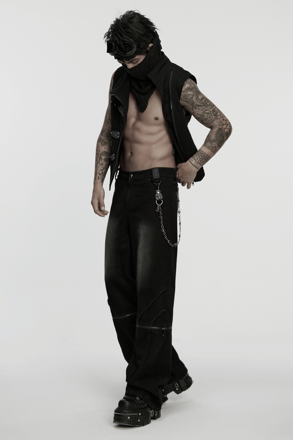Model in punk fashion with barbed wire pants and spider keychain, exuding edgy gothic style.
