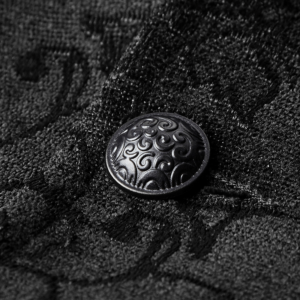 Close-up of a decorative black button on vintage jacquard fabric, showcasing intricate detailing and texture.