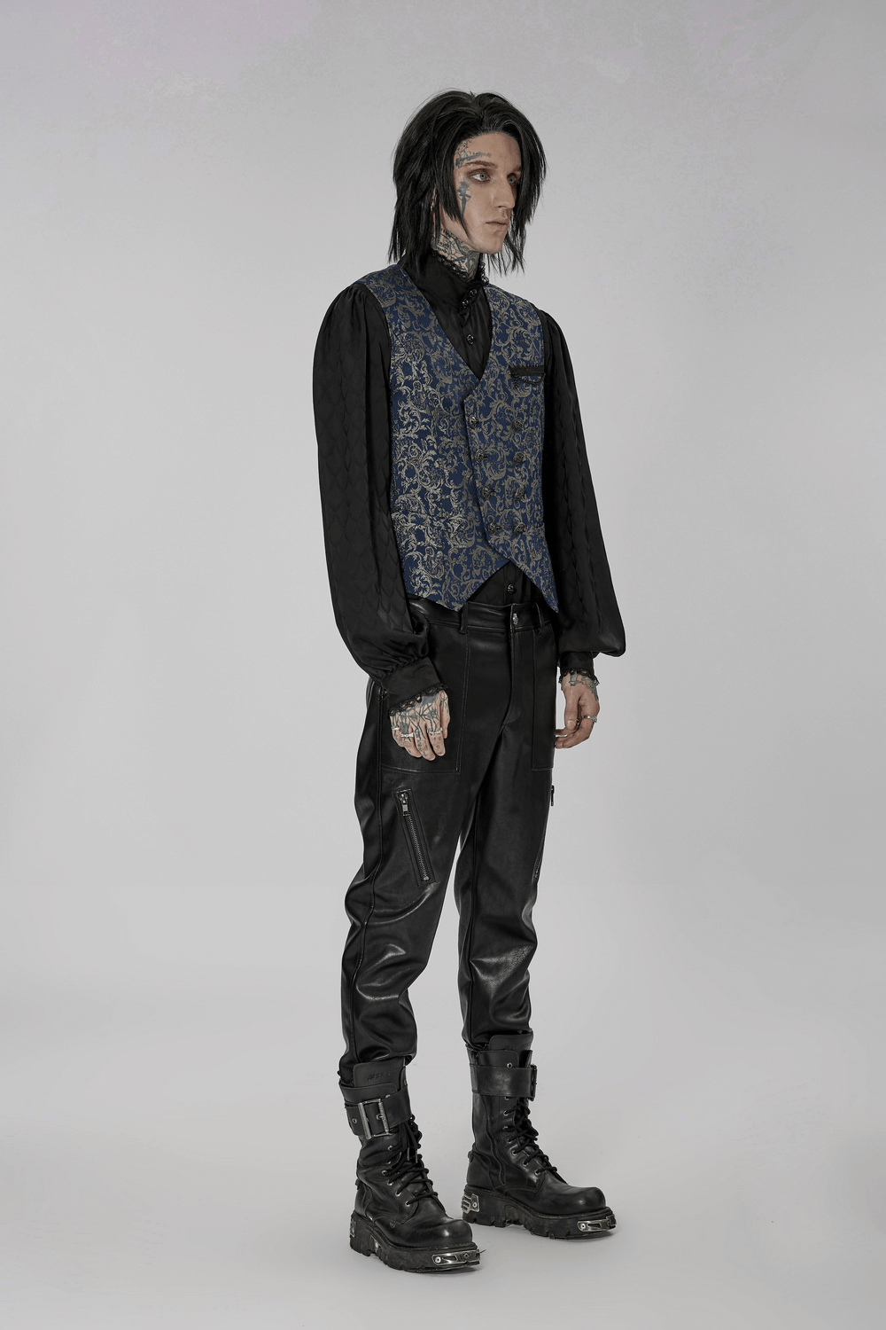 Elegant goth model in a baroque-inspired navy jacquard tailored vest with black pants and boots.