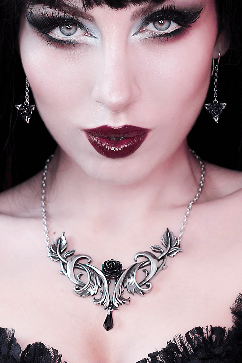 Elegant Baroque rose pendant with black Austrian crystal drop, worn by a model featuring bold makeup.