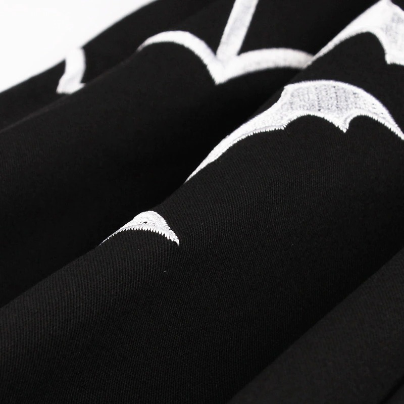 Close-up of embroidered white bats on a black gothic women's dress, perfect for Halloween celebrations.