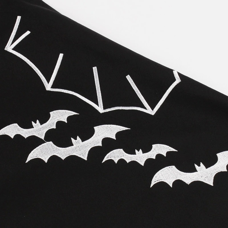 Close-up of white bat embroidery on a black fabric, perfect for a gothic Halloween dress.