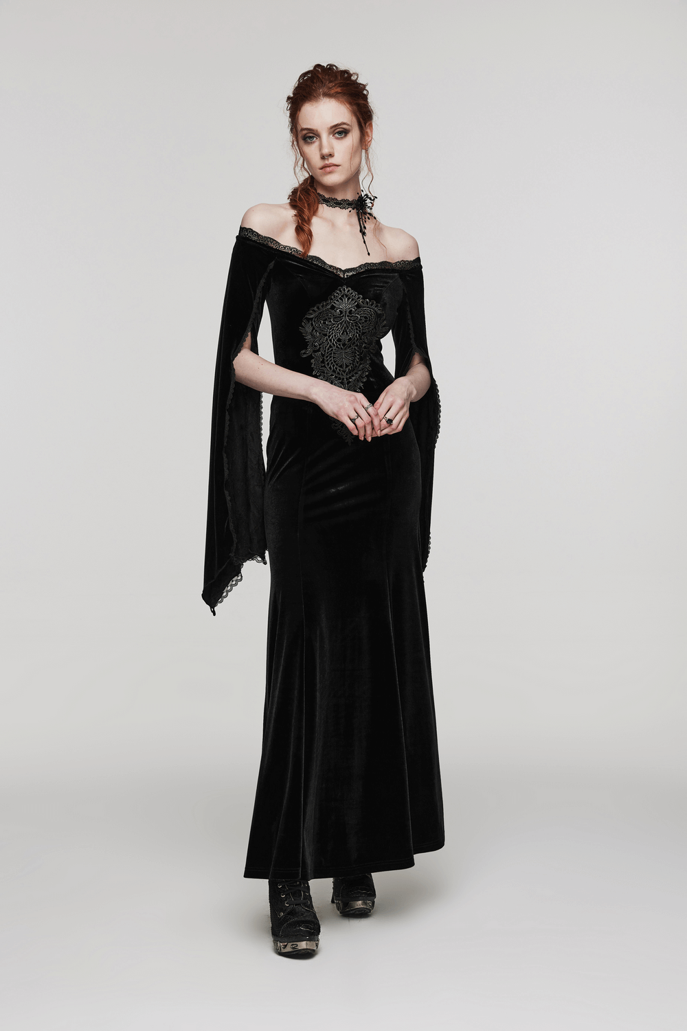 Gothic model wearing an elegant black velvet dress with an off-shoulder design and spiderweb lace accents.