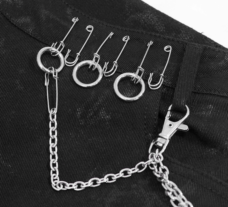 Close-up of black denim detail with silver chain and safety pins for a punk rock style.