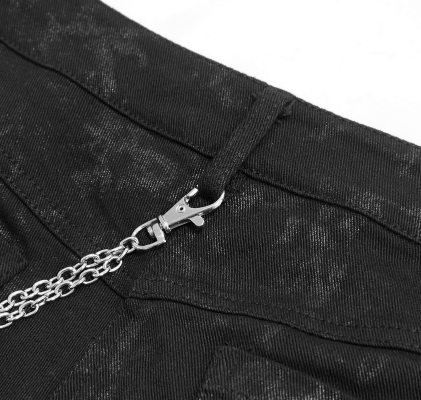 Close-up of black punk skinny jeans showcasing silver rivet and chain detailing for a stylish grunge look.