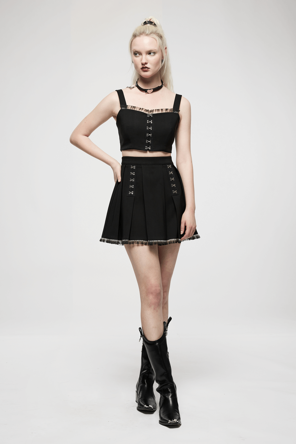Chic black A-line pleated skirt with lace detail and buckle, styled with a matching crop top and edgy accessories.
