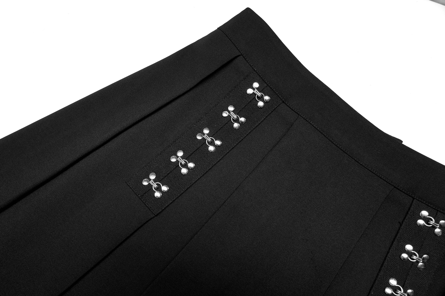 Close-up of a black A-line skirt showcasing pleats and metallic buckles for a chic edgy look.