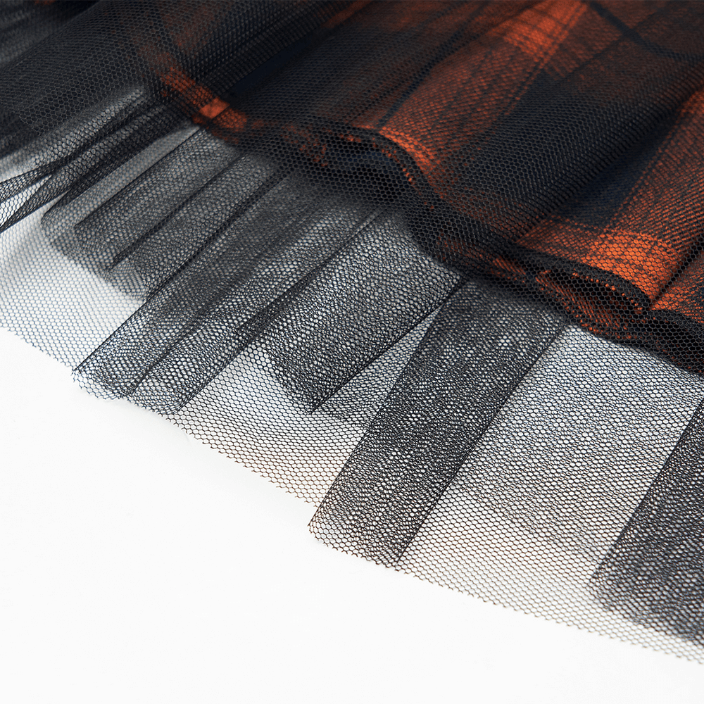 Close-up of black and orange plaid mesh skirt hem with layered tulle for a punk rave look.