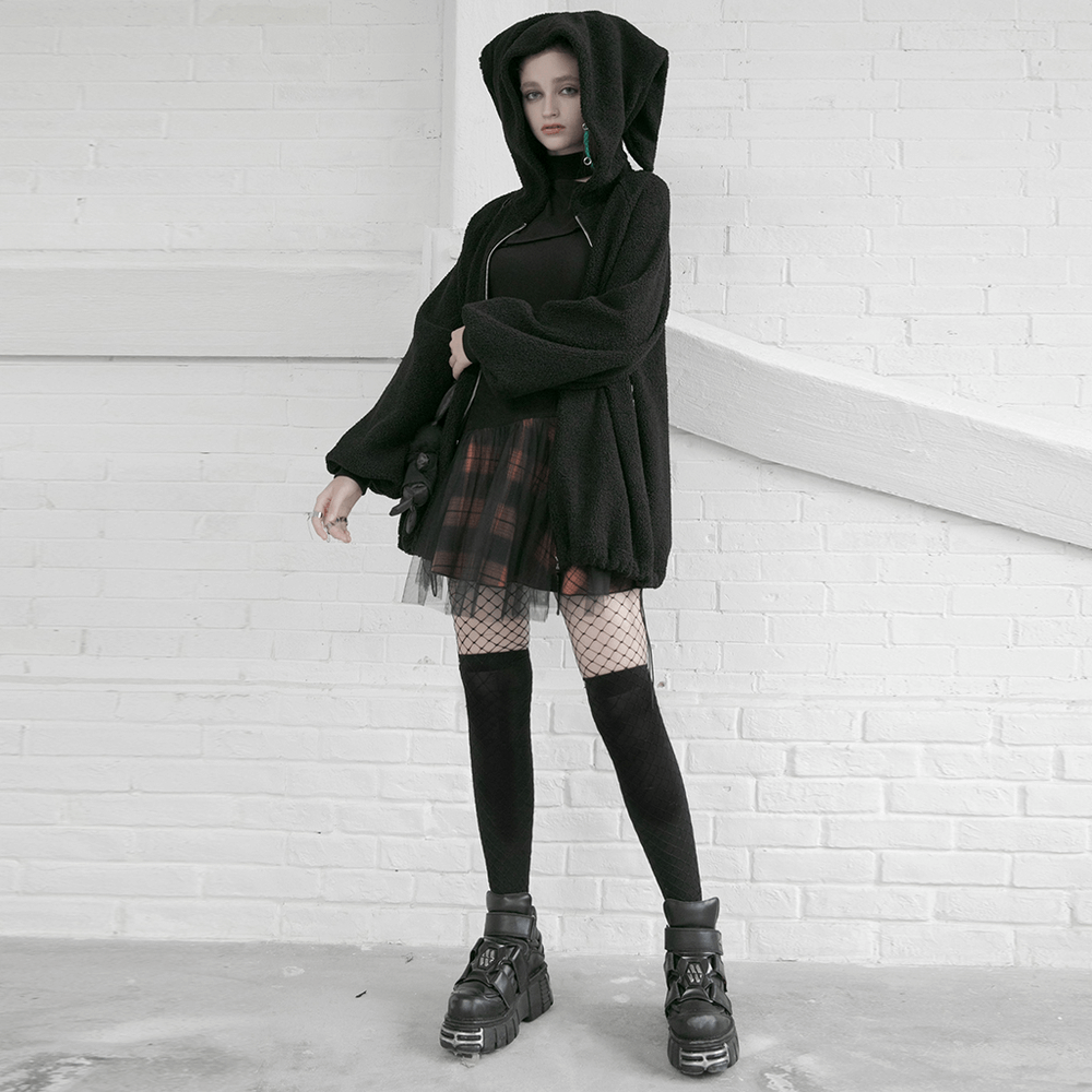Model in a black oversized jacket, wearing a black and orange plaid mesh skirt with fishnet stockings and chunky boots.