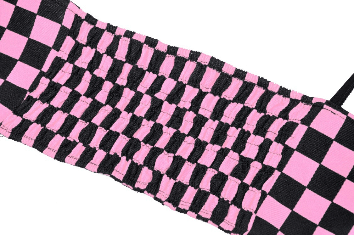 Close-up of black and pink checkered fabric of punk rock halter crop top with strappy design.