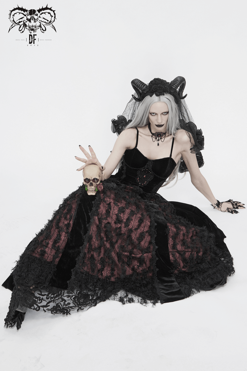 Gothic model in black and red velvet dress, holding a skull, showcasing elegant lace details and dramatic styling.