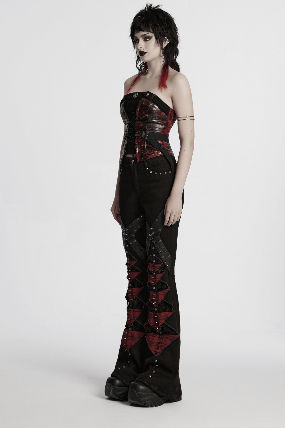 Gothic black and red plaid flared pants with studs, featuring mesh and spikes, embodying punk street style.