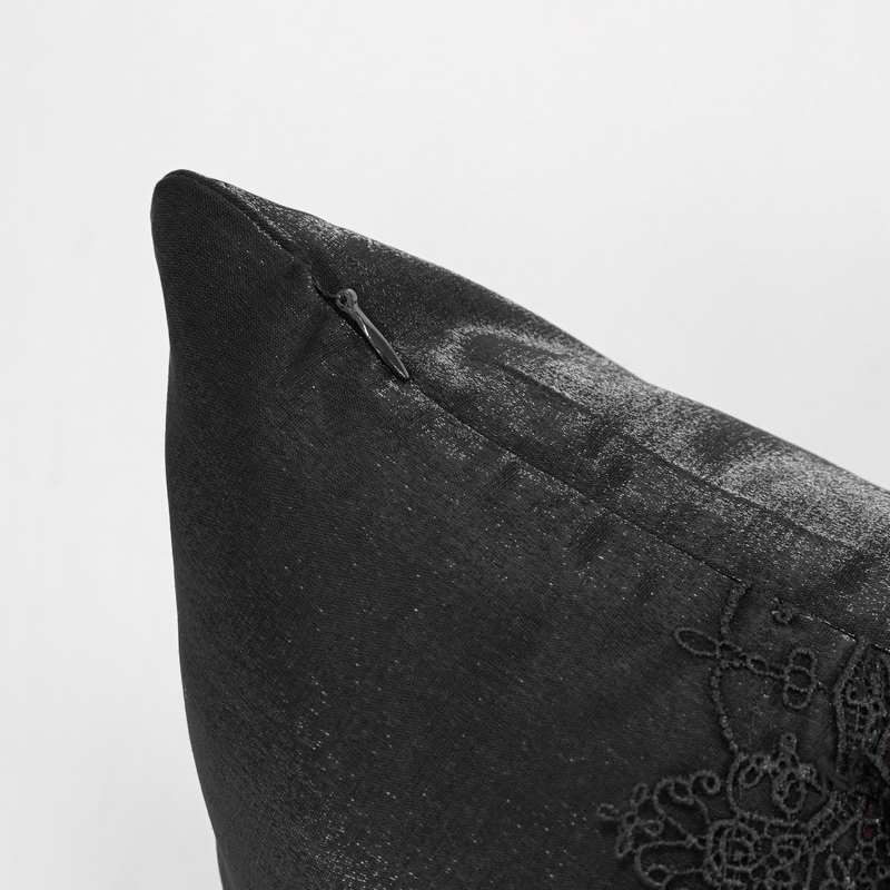 Close-up of a black and red satin pillow featuring decorative lacing for gothic-style decor.