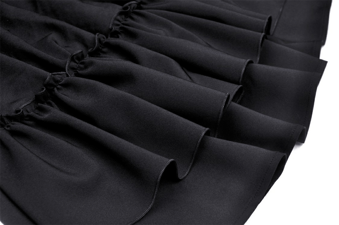 Close-up of black fabric ruffles showcasing elegant texture and design of gothic dress skirt.