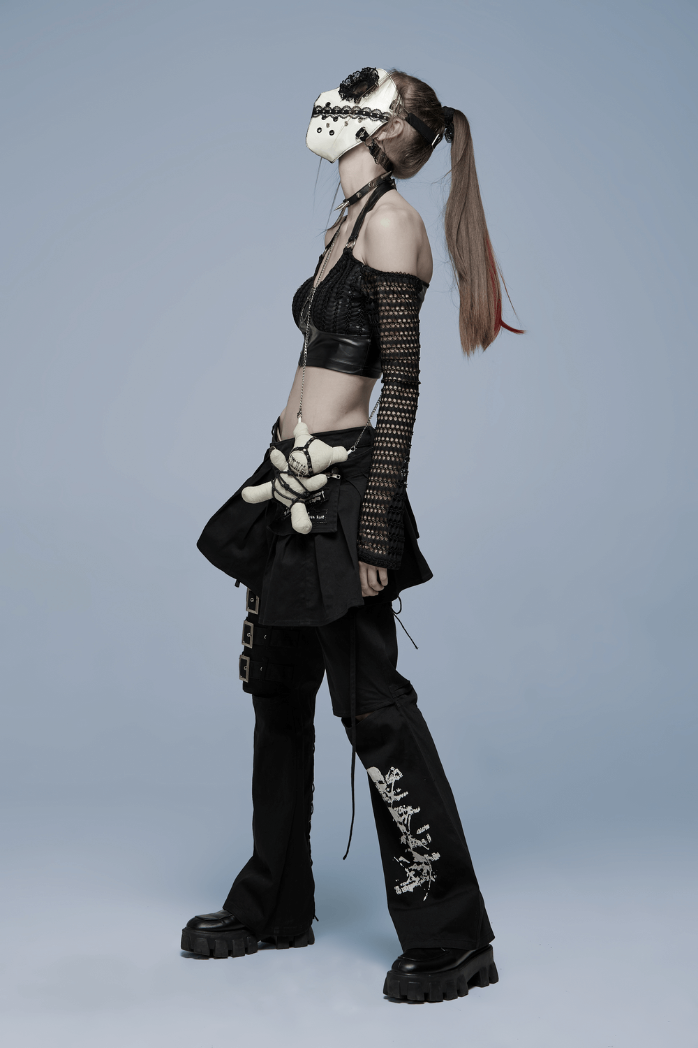 Stylish model in gothic mask, crop top, and high-waisted pants, showcasing dark Lolita fashion with edgy flair.